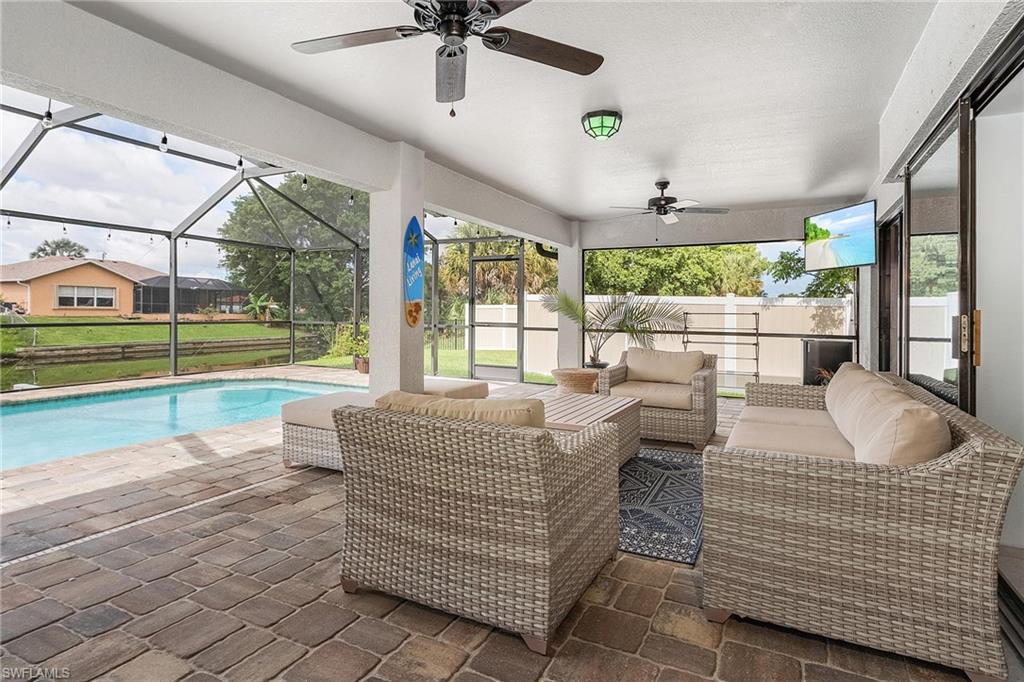 View of patio featuring a fenced in pool, an outdoor hangout area, glass enclosure, ceiling fan, and fence