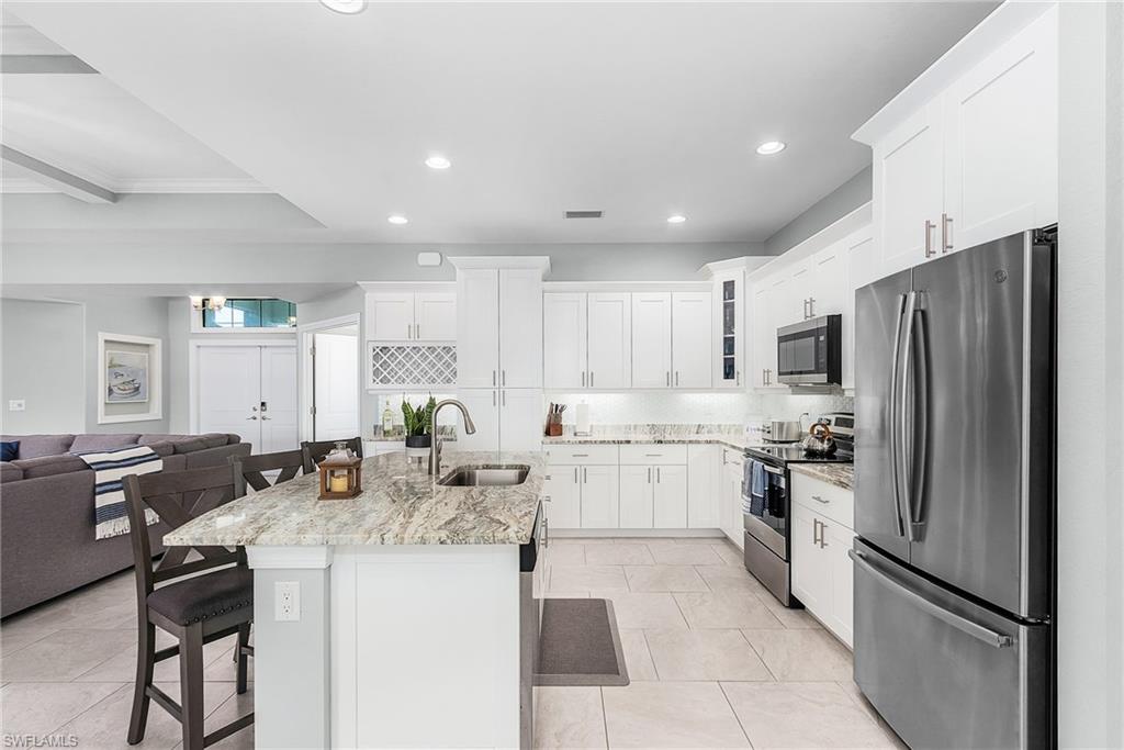Kitchen with stainless steel appliances, decorative backsplash, open floor plan, a sink, and a kitchen breakfast bar