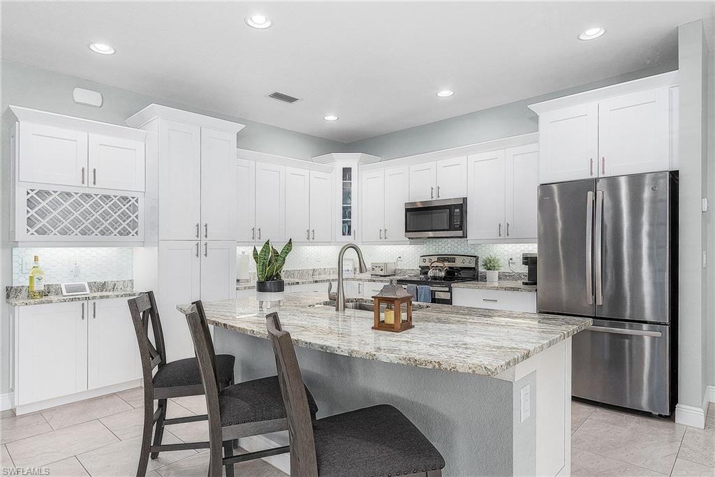 Kitchen with white cabinets, appliances with stainless steel finishes, backsplash, and a sink