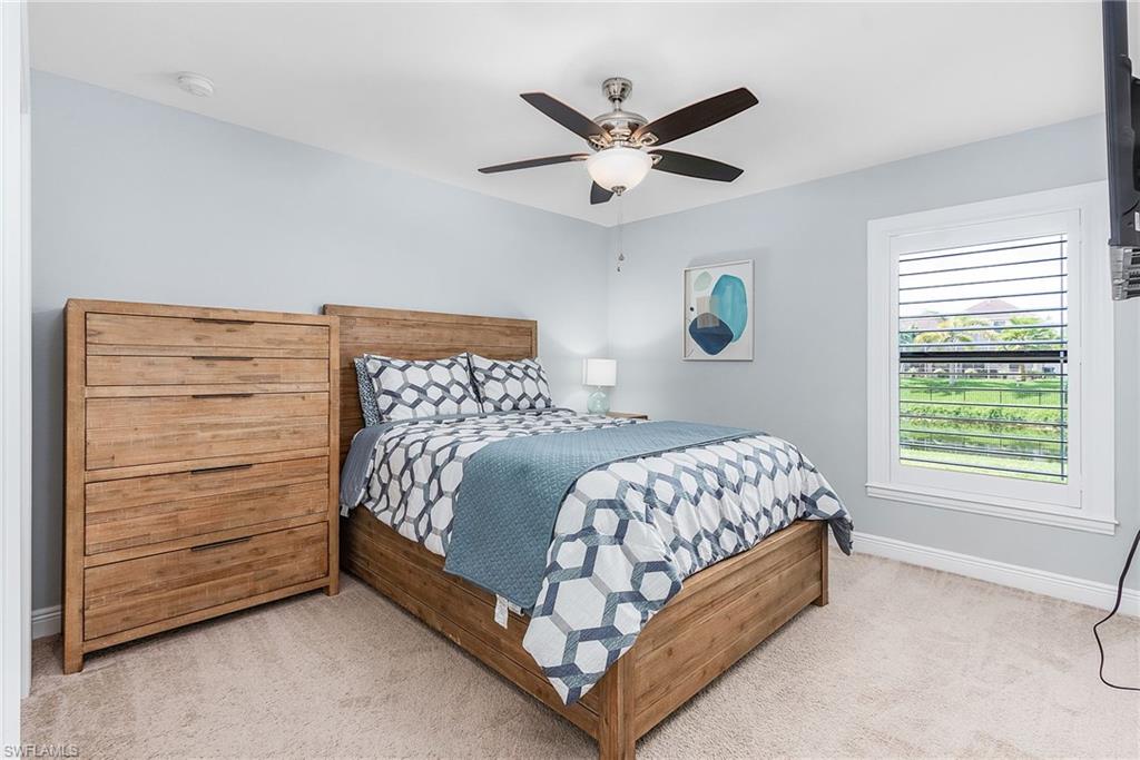Bedroom with light carpet, ceiling fan, and baseboards