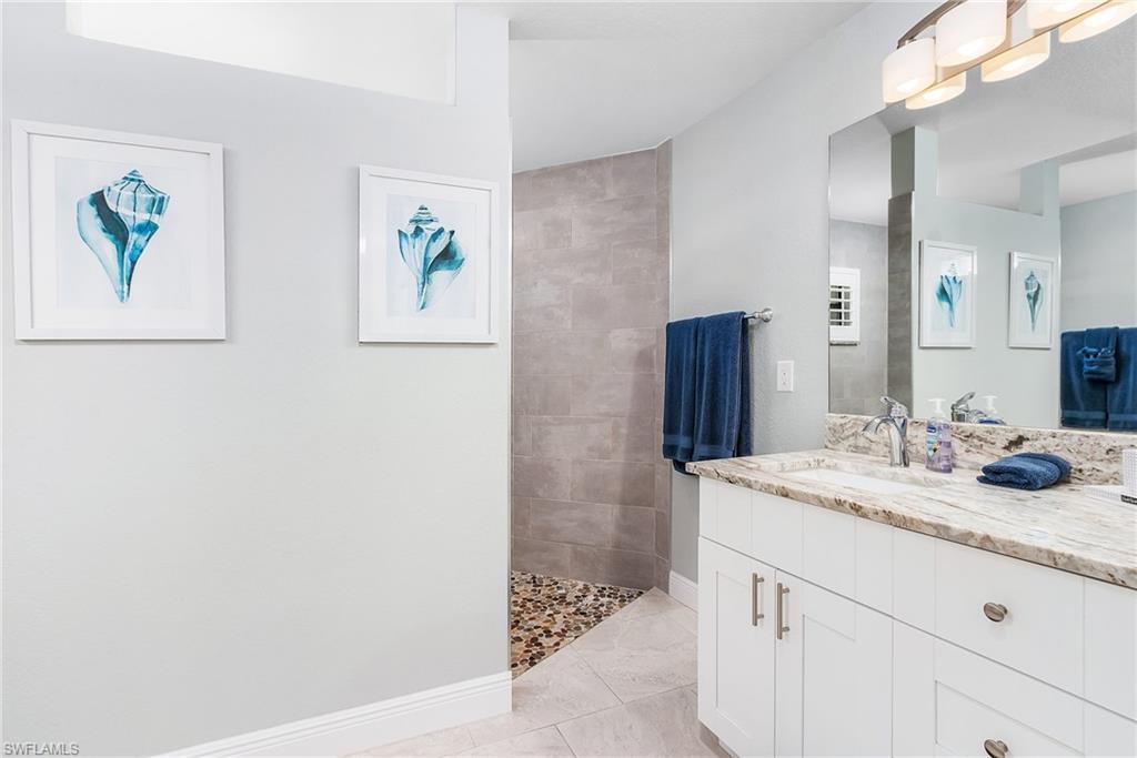 Full bath featuring a walk in shower, tile patterned flooring, vanity, and baseboards