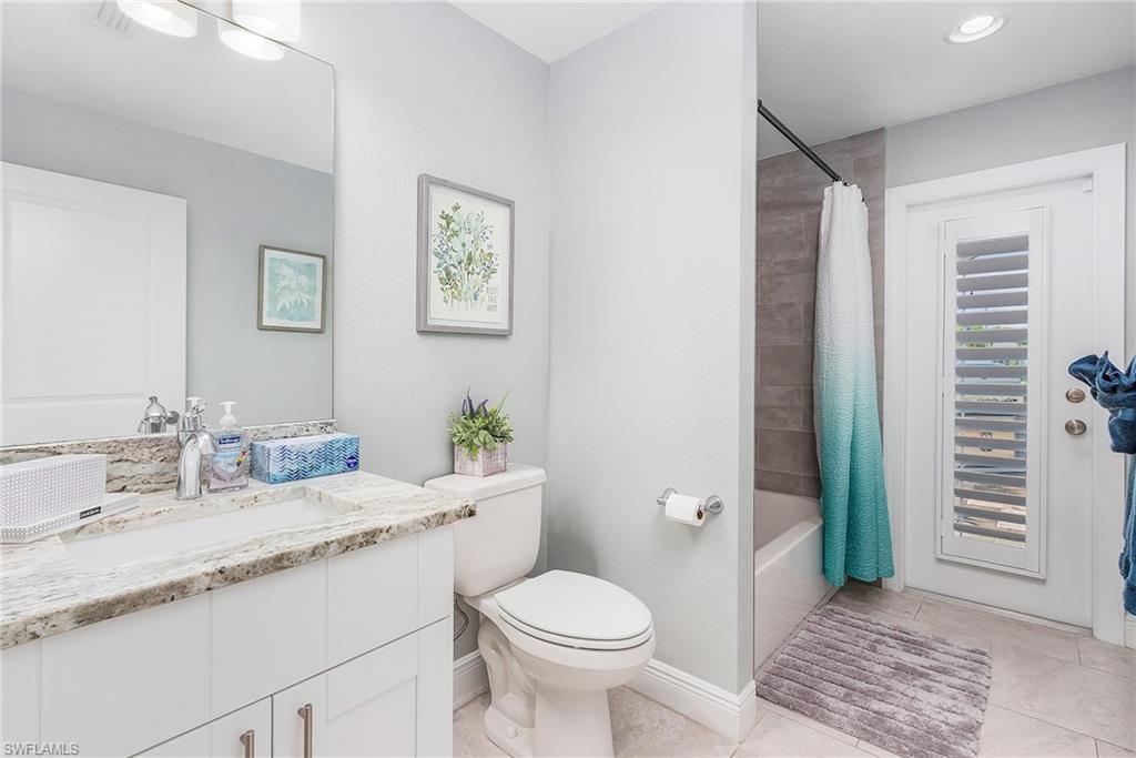 Bathroom featuring baseboards, toilet, tile patterned flooring, shower / bath combination with curtain, and vanity