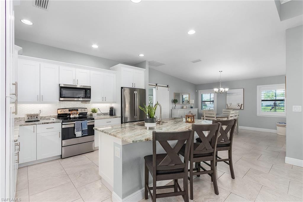 Kitchen with stainless steel appliances, tasteful backsplash, visible vents, a barn door, and light stone countertops