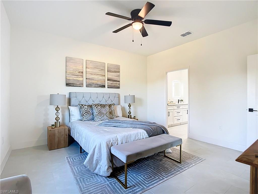 Spacious room featuring light tile flooring, a dark ceiling fan with integrated lighting, and a doorway leading to a bathroom with white cabinetry and dark hardware