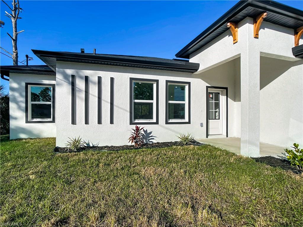 Modern white stucco exterior with contrasting black trim, multiple windows, a white paneled entry door, and decorative wood corbels