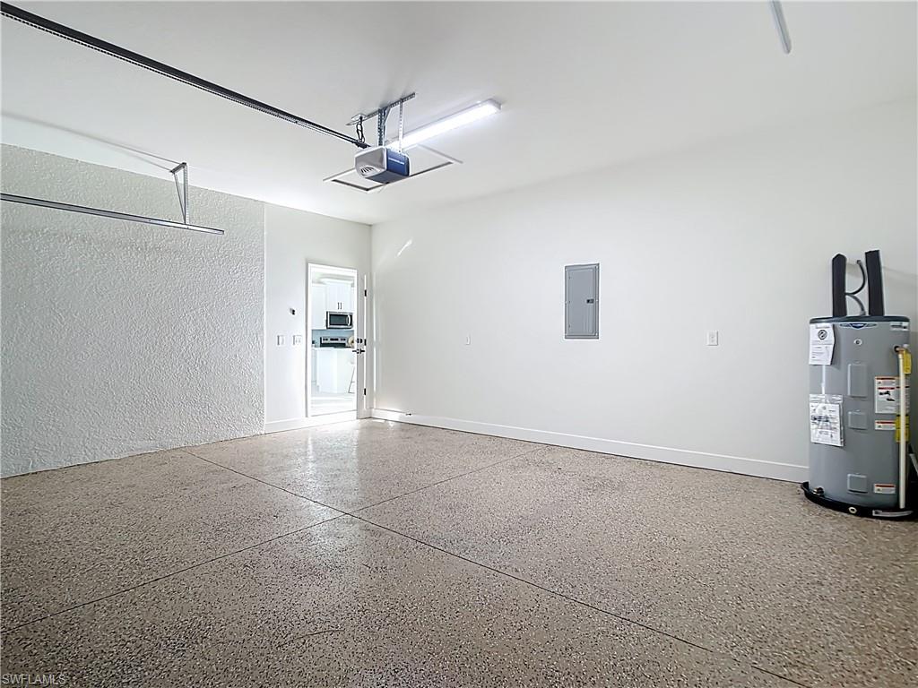 Spacious garage featuring a durable aggregate-finish floor, a garage door opener, and a water heater