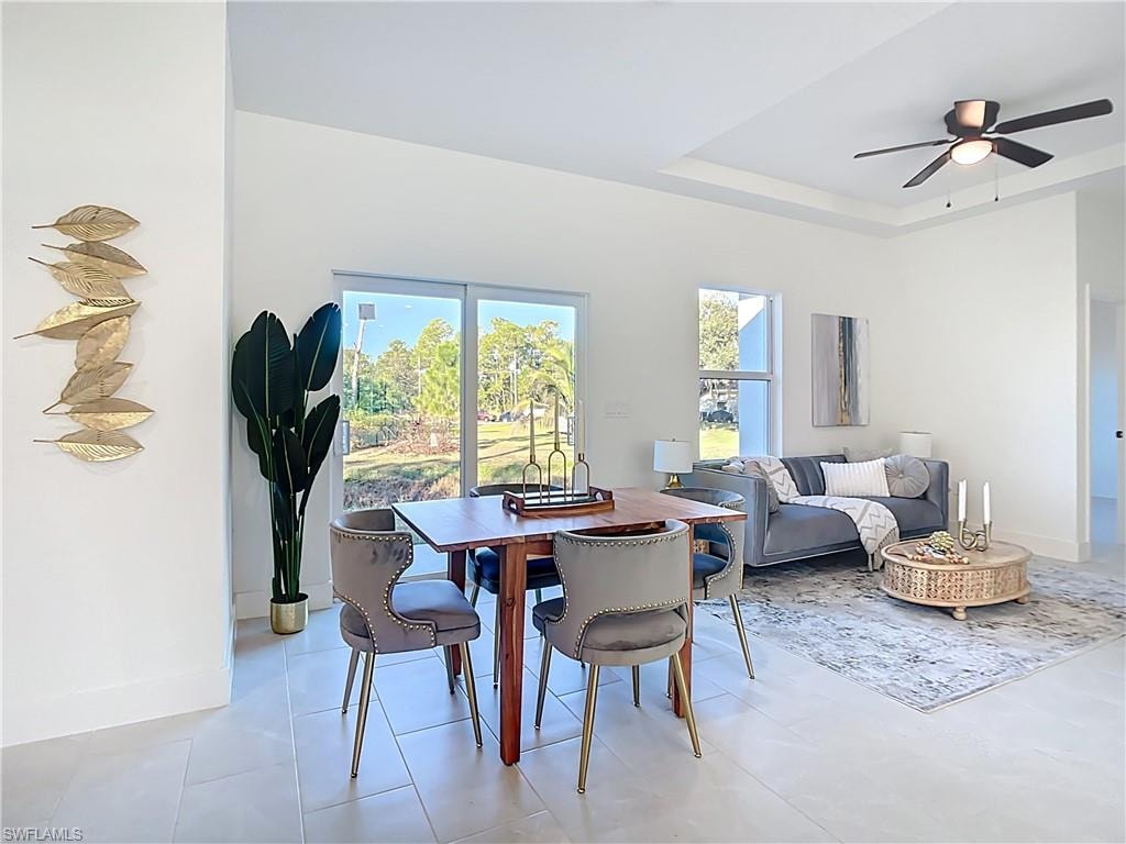 Open-concept living area featuring a tray ceiling, ceiling fan, and large sliding glass doors