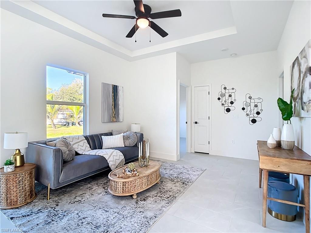 Living area featuring a tray ceiling with a ceiling fan, recessed lighting, and light-toned tile flooring