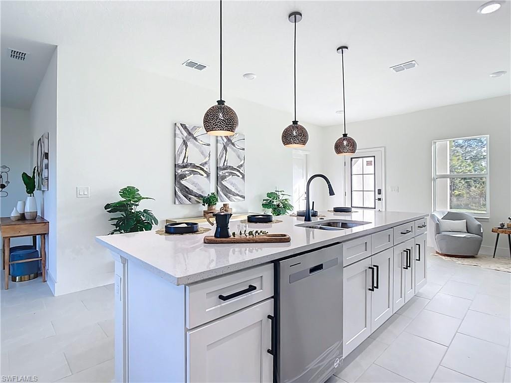 Spacious kitchen island featuring a deep sink with a matte black faucet, integrated dishwasher, ample cabinetry with black hardware, and three decorative pendant lights