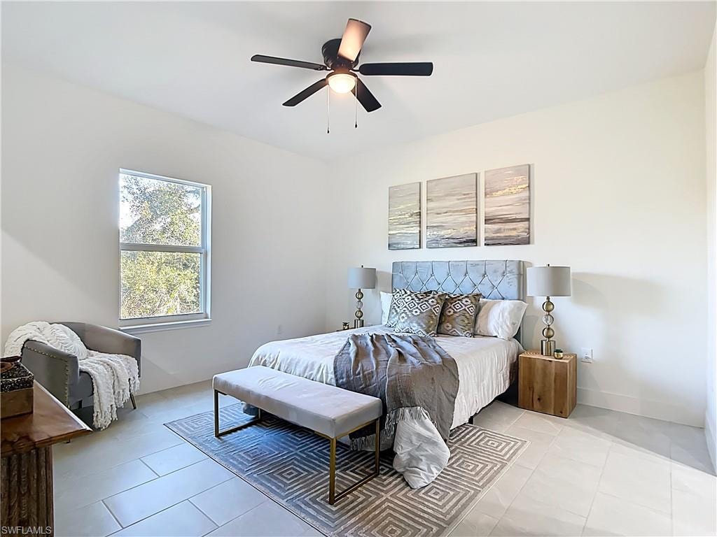 Spacious room featuring light-toned tile flooring, a large window, a ceiling fan with integrated lighting, and crisp white walls