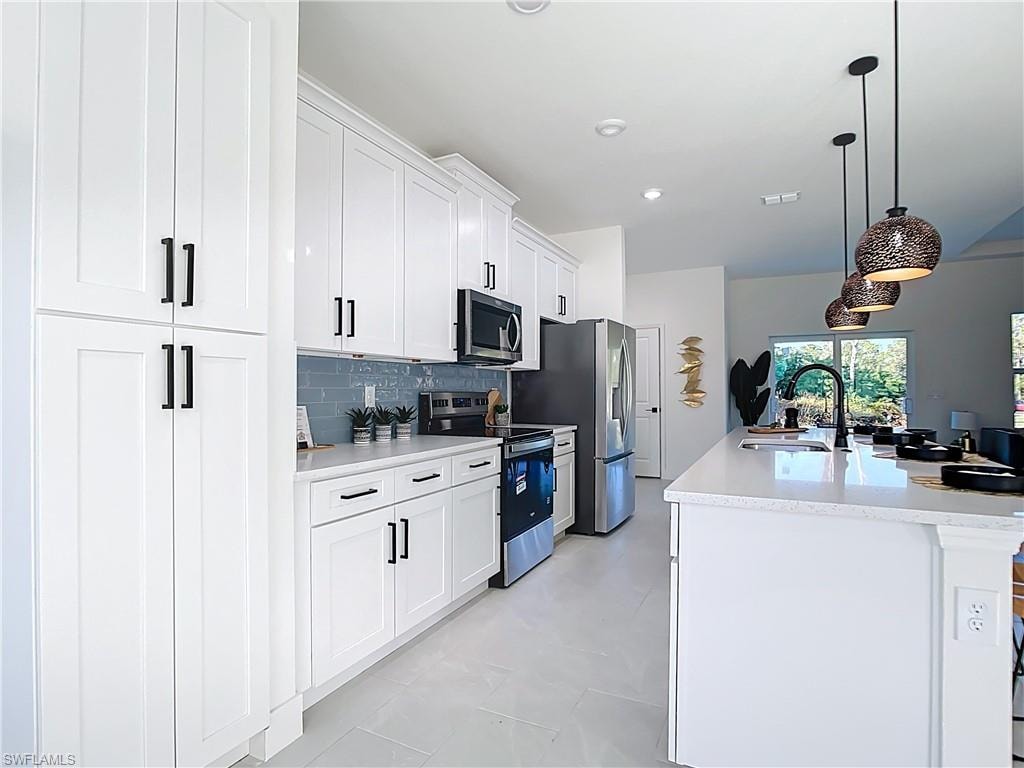 Kitchen featuring white shaker cabinetry, stainless steel appliances, light-toned countertops, and a subway tile backsplash