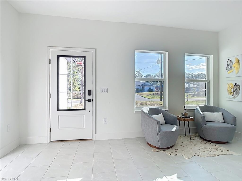 Entryway featuring a white paneled door with glass inserts and black hardware, paired with white tile flooring