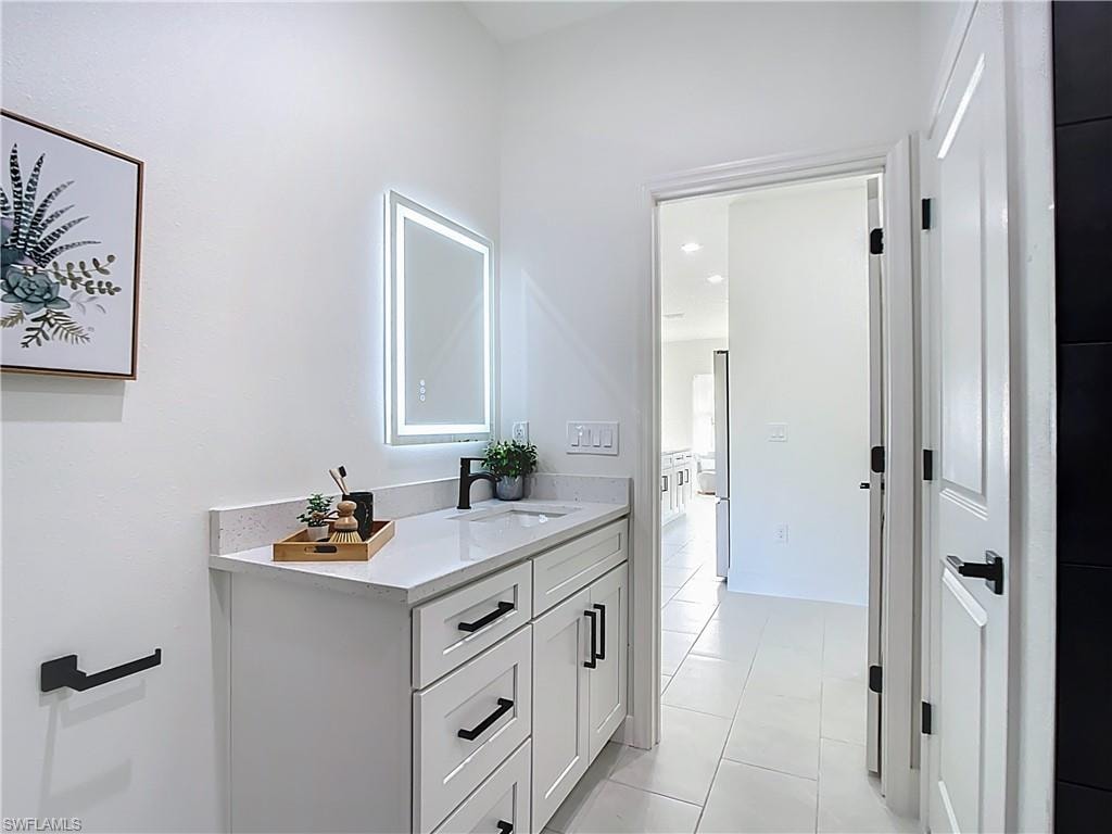 Bathroom vanity featuring a quartz countertop, integrated sink, and matte black faucet