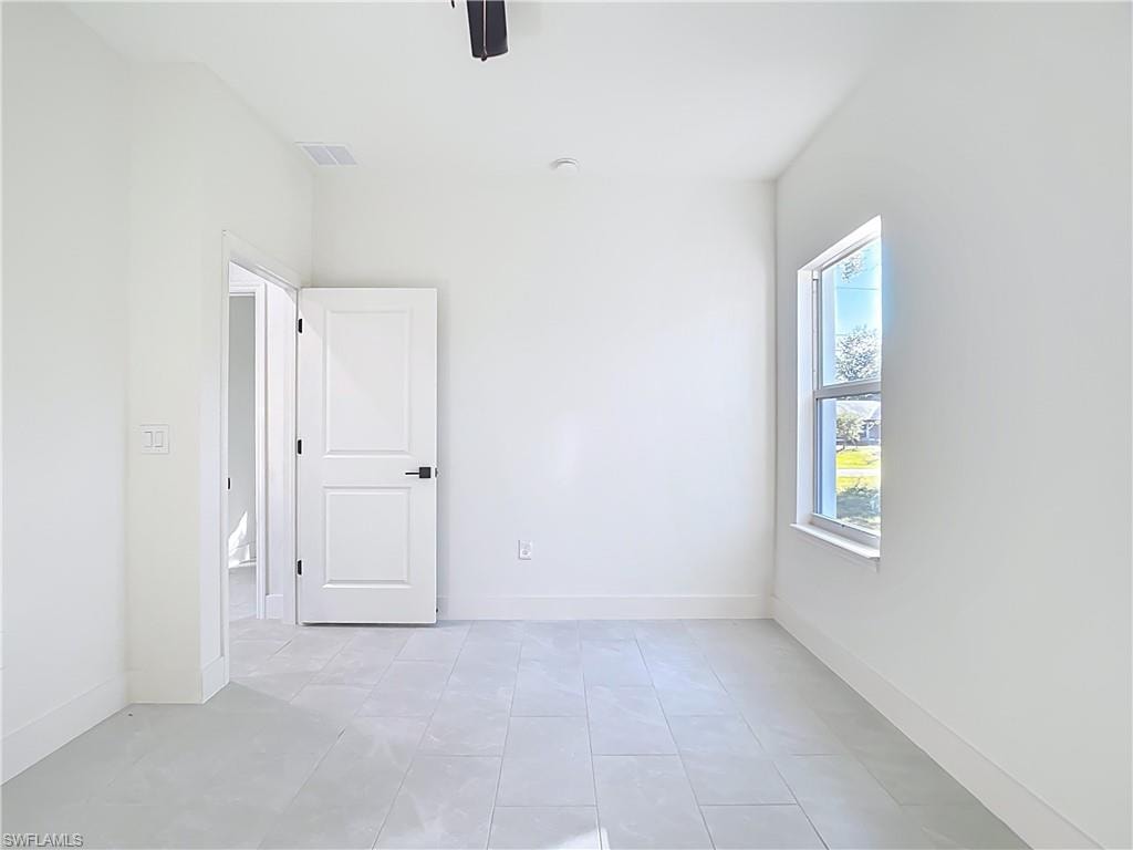 Bright room featuring light-colored tile flooring, white painted walls, a white paneled door with dark hardware, and a double-hung window with a white frame