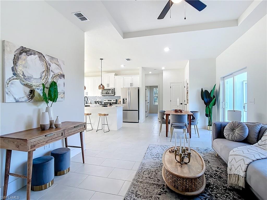 Spacious open-concept living area featuring high ceilings, contemporary light tile flooring, and sliding glass doors