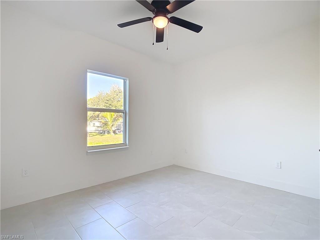 Bright room with light tile flooring and a ceiling fan