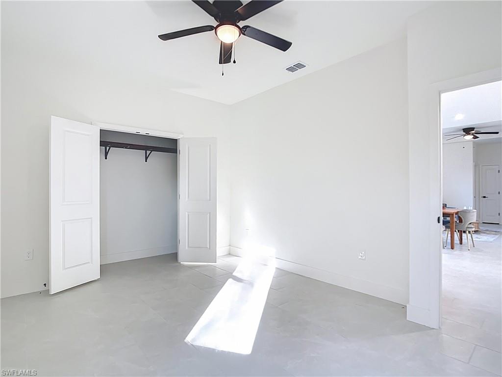 Bright room featuring light-colored tile flooring, a black ceiling fan with an integrated light, and a double-door closet with an interior hanging rod