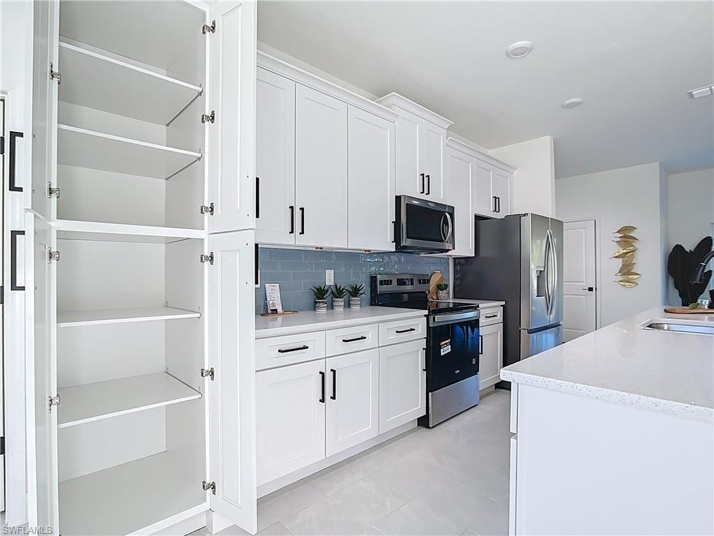 White shaker cabinetry with black hardware, complementing a blue subway tile backsplash