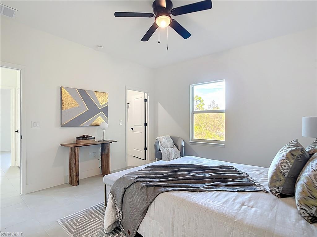 Bright room featuring an overhead ceiling fan with lighting, a large window, and light-toned tile flooring