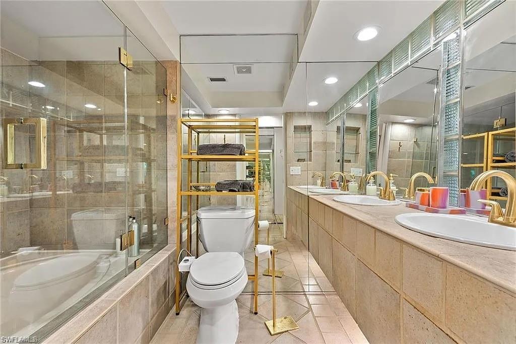 Bathroom with toilet, a relaxing tiled tub, tile patterned floors, tiled shower, and double vanity