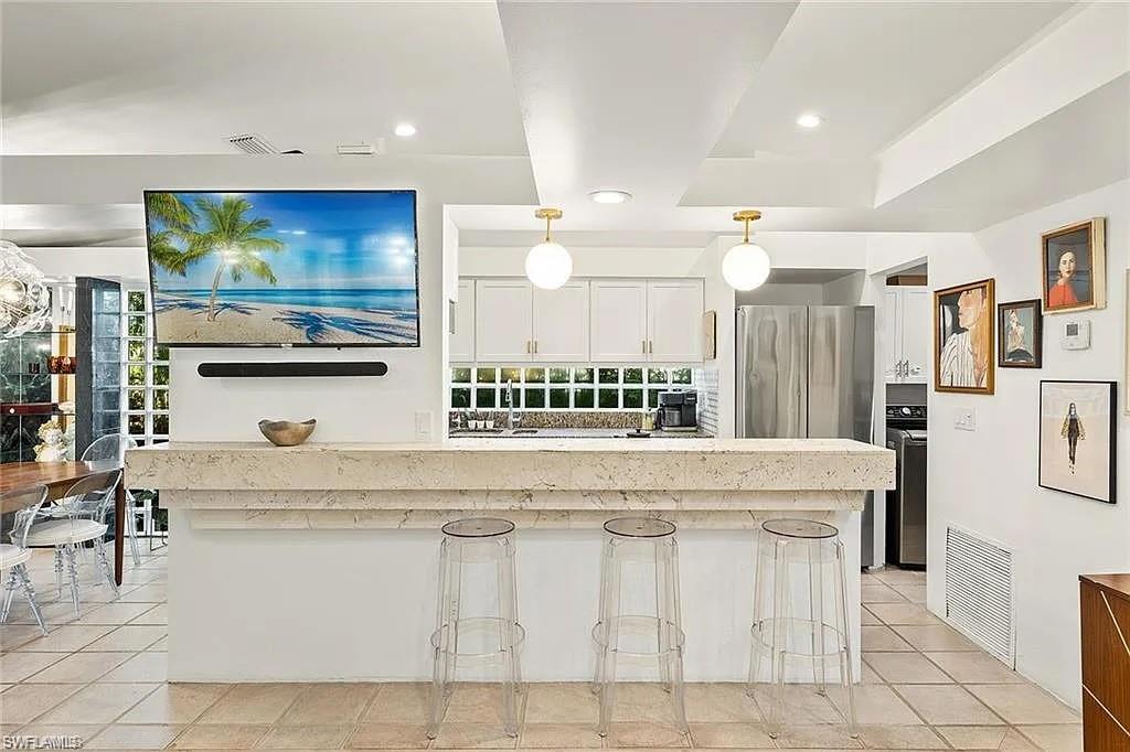Kitchen with white cabinetry, decorative light fixtures, a breakfast bar area, light tile patterned floors, and recessed lighting
