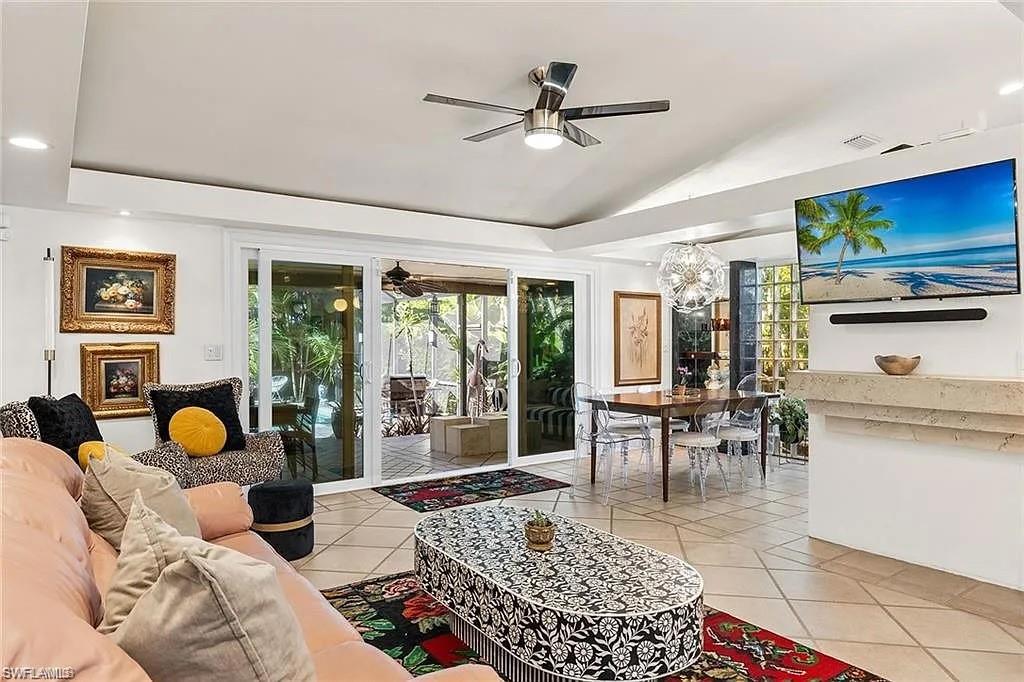 Living room with ceiling fan, lofted ceiling, light tile patterned flooring, and plenty of natural light
