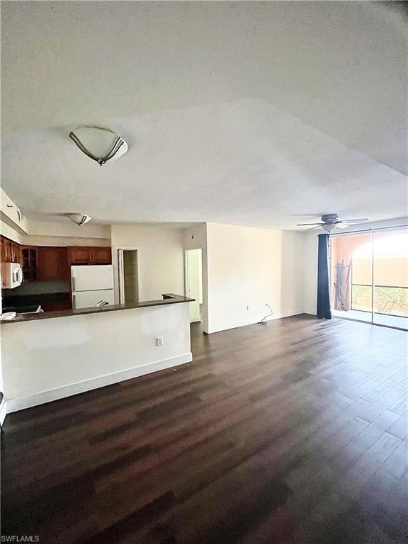Spacious living area featuring dark wood-finish flooring, a contemporary ceiling fan, and sliding glass doors to the exterior