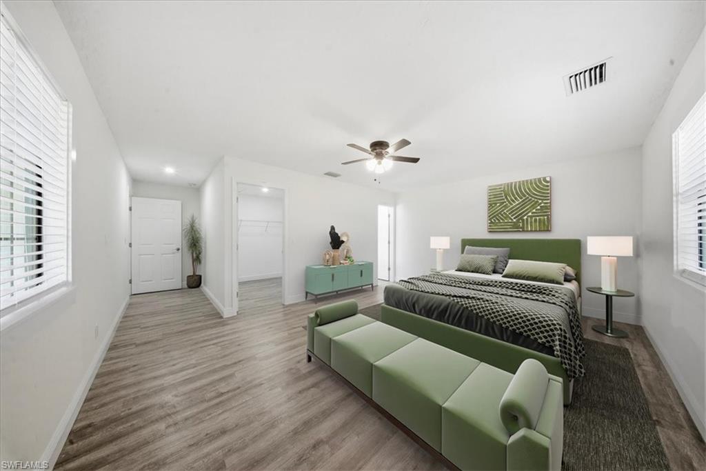 Bedroom featuring wood finished floors, a spacious closet, and ceiling fan