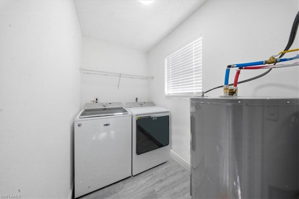 Laundry area featuring water heater, light wood-style flooring, and washer and dryer