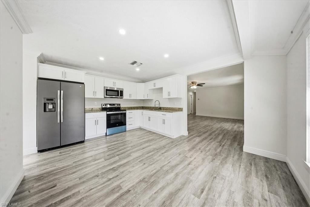 Kitchen featuring appliances with stainless steel finishes, white cabinets, light wood finished floors, recessed lighting, and open floor plan
