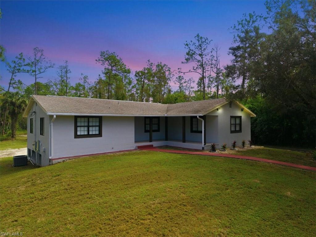 Ranch-style home featuring covered porch, a yard, and stucco siding