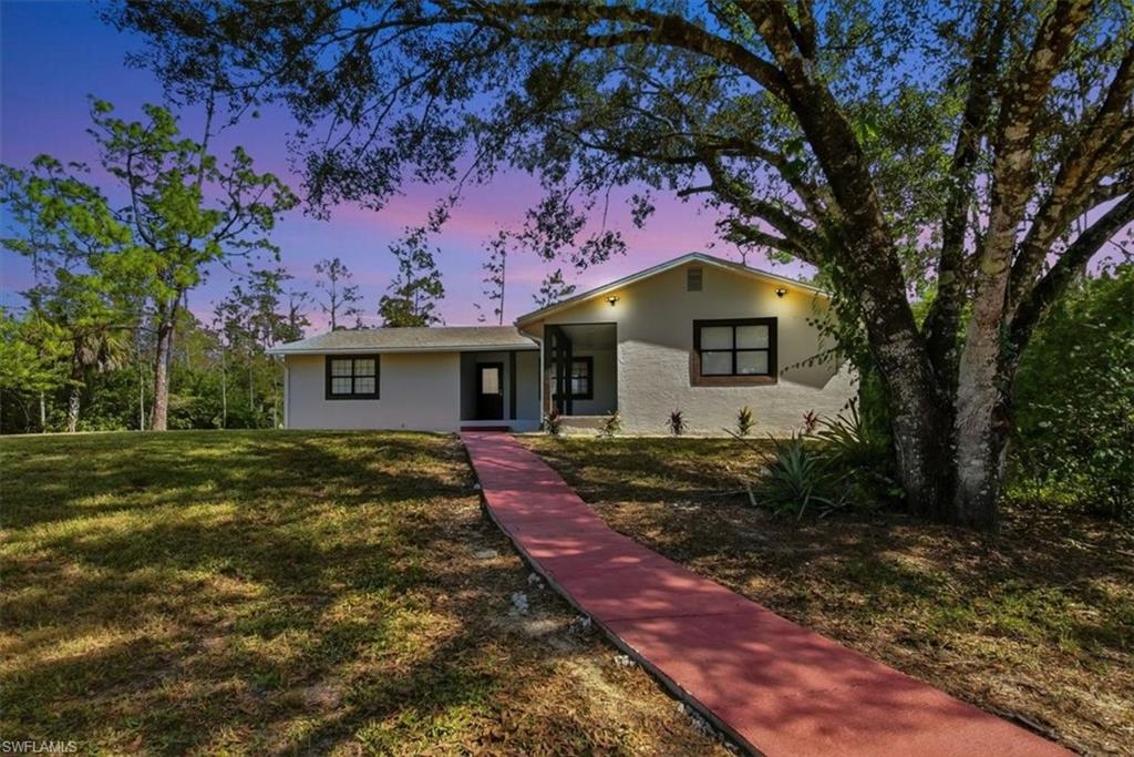 View of front of property featuring a lawn and stucco siding