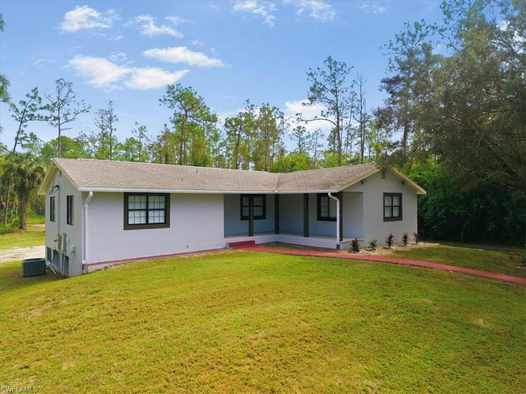 View of front of home with covered porch, a front lawn, and stucco siding