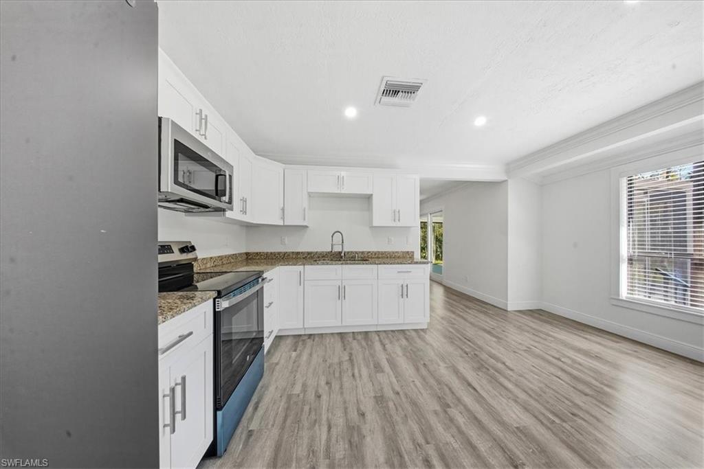 Kitchen with stainless steel appliances, light wood-style flooring, recessed lighting, white cabinetry, and healthy amount of natural light