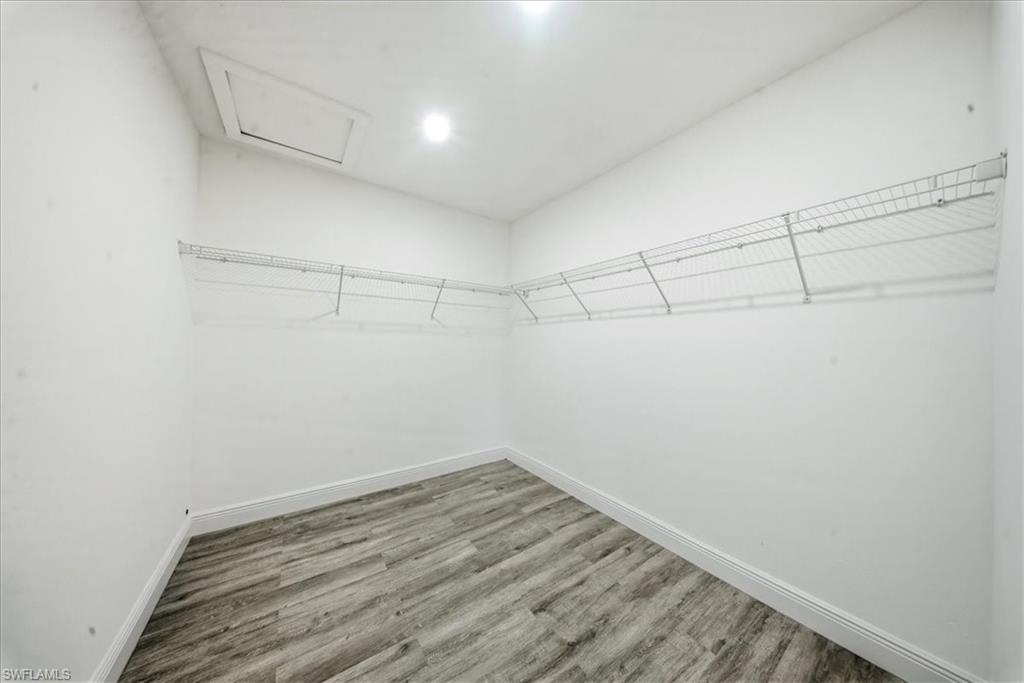 Walk in closet with attic access and light wood-style floors