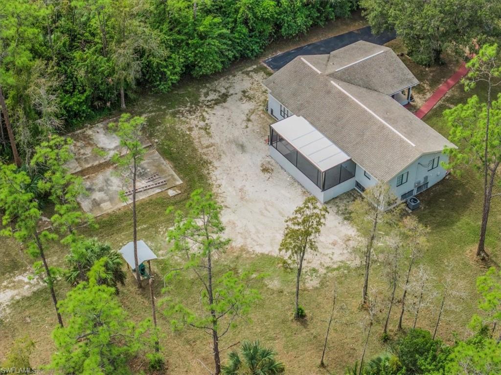 Aerial view of property and surrounding area with a tree filled landscape