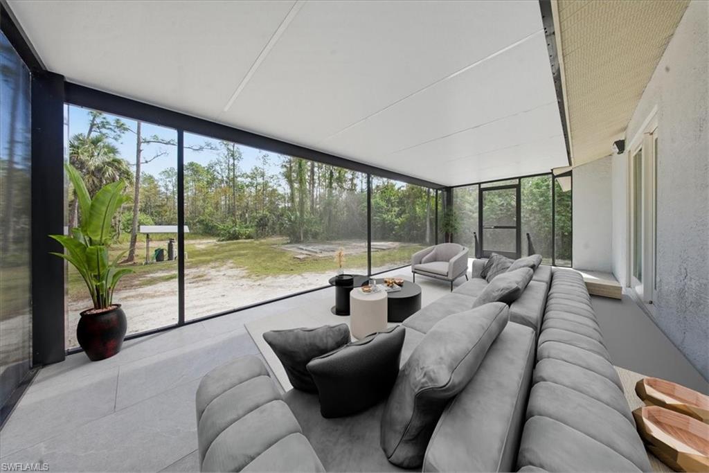 Sunroom featuring an outdoor hangout area, a wall of windows, and view of scattered trees