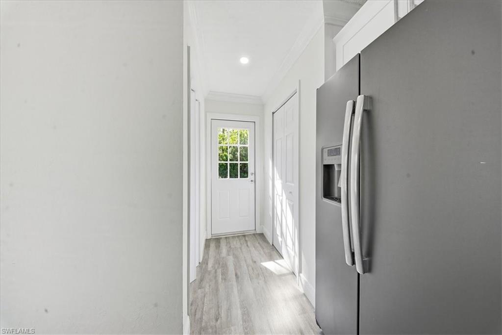Corridor with crown molding, light wood-type flooring, and recessed lighting