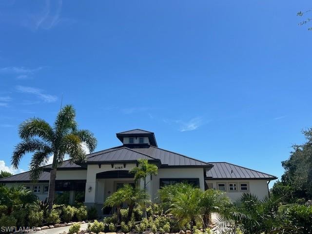 View of front of home featuring an attached garage, metal roof, a standing seam roof, and stucco siding