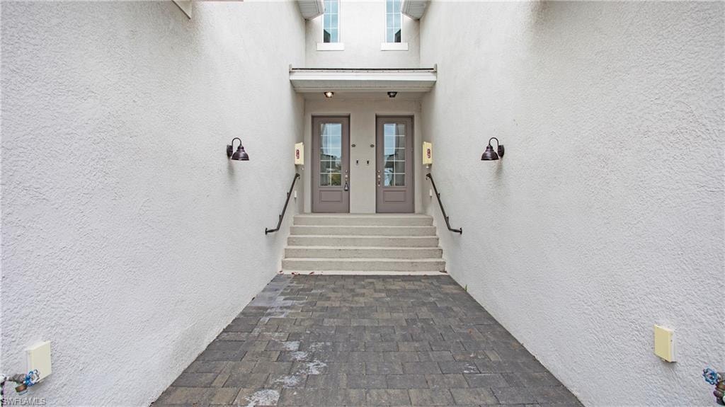 Paver walkway leading to a stucco exterior with dual entry doors
