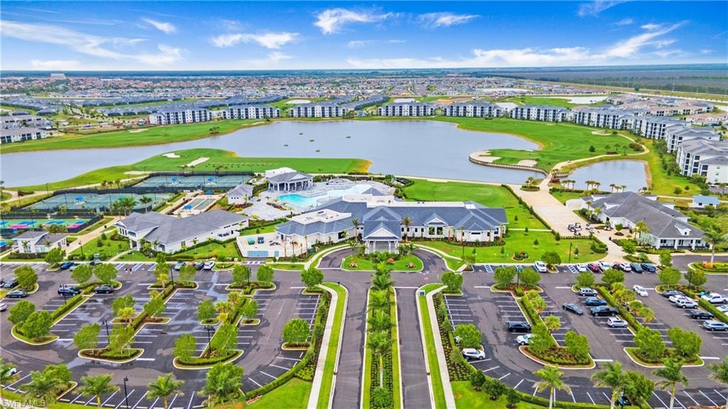 Expansive aerial showcasing a master-planned community featuring a large lake, manicured golf course, multiple tennis courts, and a central clubhouse with a swimming pool
