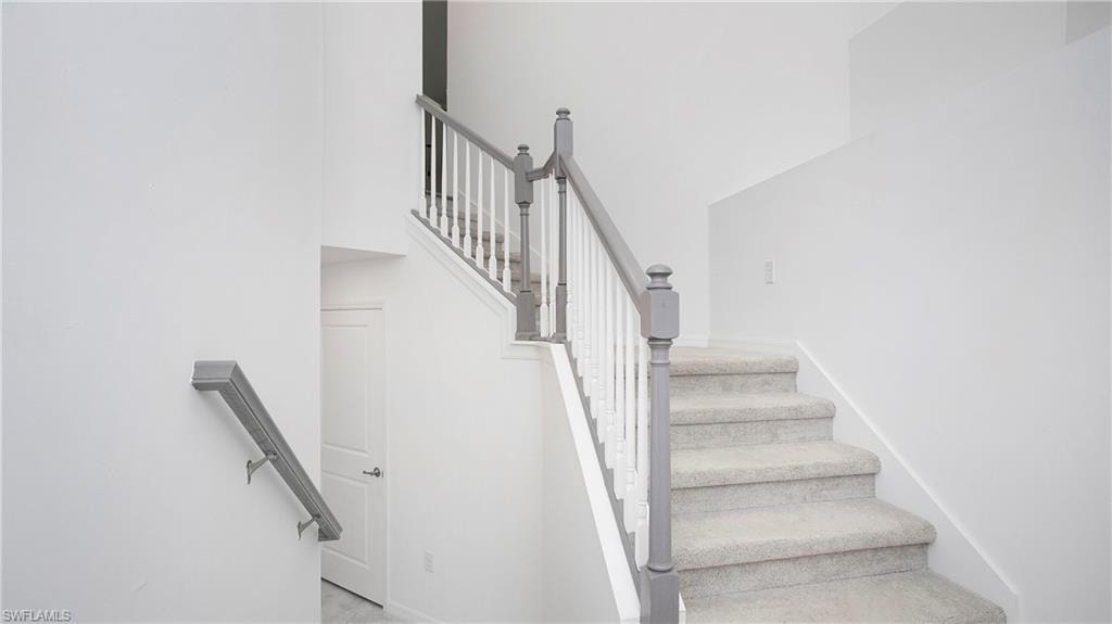 Carpeted staircase featuring a painted wood balustrade with square pickets and a grey handrail