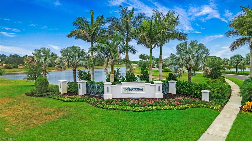 Community entrance signage framed by lush landscaping and mature palm trees