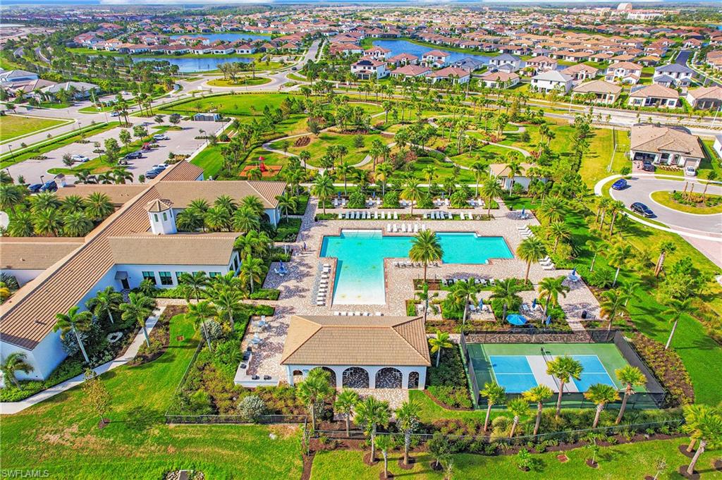 Expansive community amenity center featuring a substantial swimming pool, tennis court, and lush landscaping