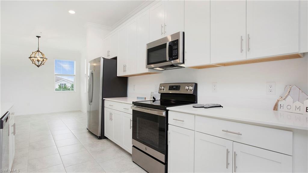 Modern kitchen featuring white shaker cabinetry, stainless steel appliances, and light-toned tile flooring