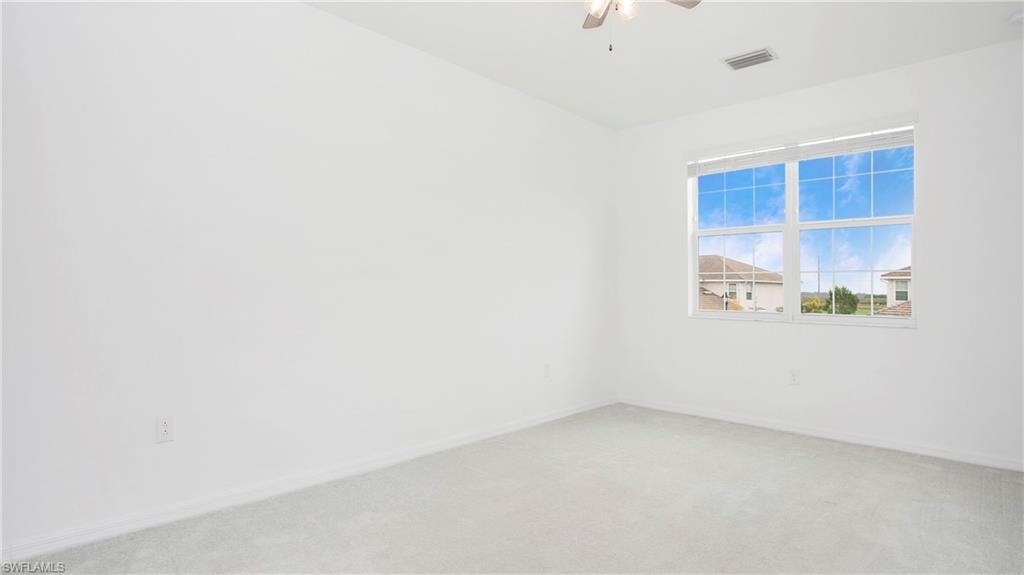 Spacious interior room featuring light gray carpet flooring and white walls