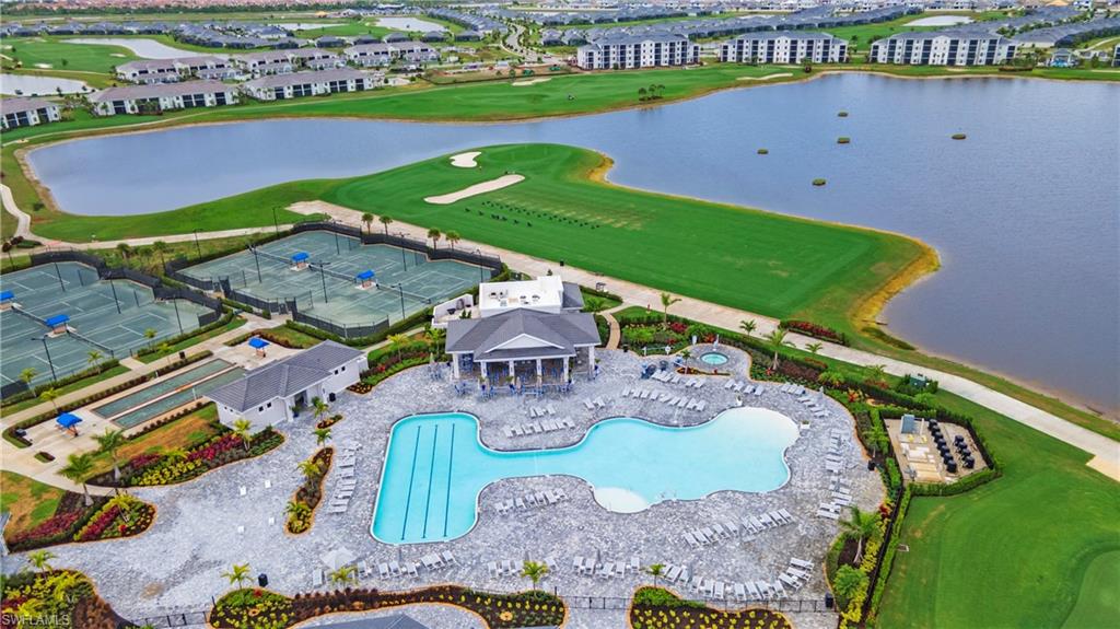 Expansive community recreation area featuring a large, multi-section swimming pool, a separate spa, multiple tennis courts, bocce ball courts, and manicured green spaces