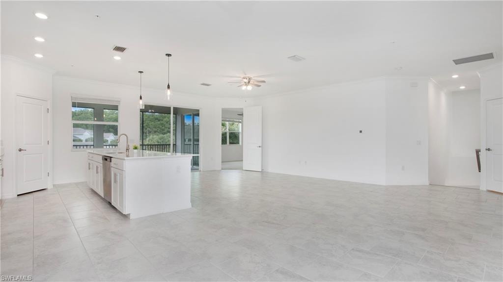 Spacious open-concept living area featuring light-toned tile flooring, recessed lighting, and a ceiling fan