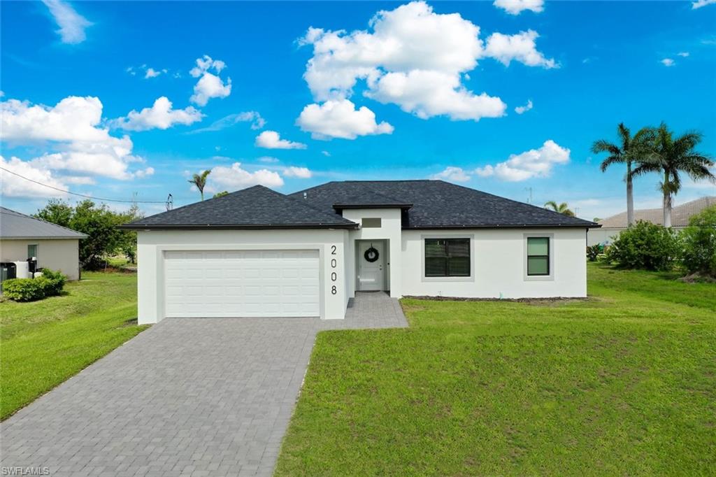 View of front of house with stucco siding, a front lawn, decorative driveway, and an attached garage