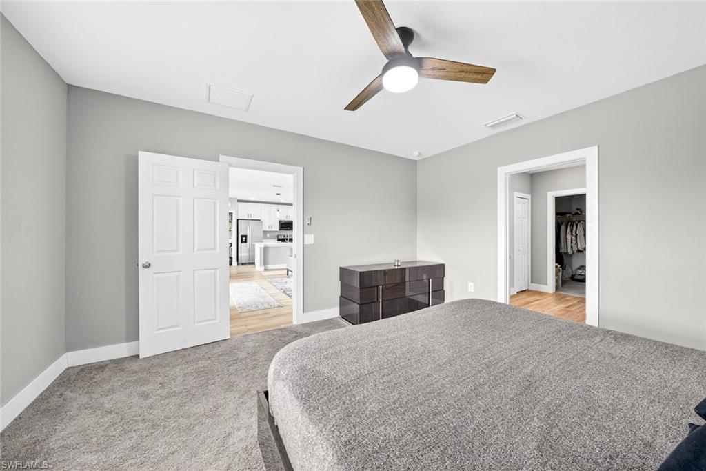 Bedroom with stainless steel fridge with ice dispenser, ceiling fan, and light carpet